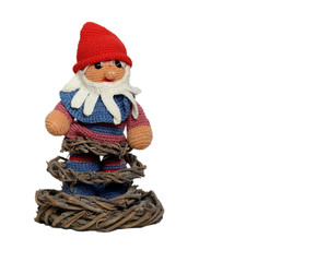 A hand made elf with red cap and beard standing on a stand made of tree roots. Gnome isolated,
