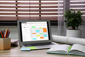 Laptop with calendar on wooden table in office