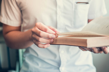 Young men wear white shirts A man standing reading a university library reading and relax Blurred background, horizontal, film effect