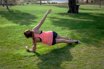 Fototapeta premium Mature 40s years old woman leads a healthy lifestyle outdoor on the green grass at the park. Middle aged sport and active female dressed sportswear practice fitness exercise