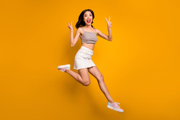 Fototapeta na wymiar Full length body size turned photo of cheerful excited cute pretty girl showing double v-sign running jumping isolated vivid color background