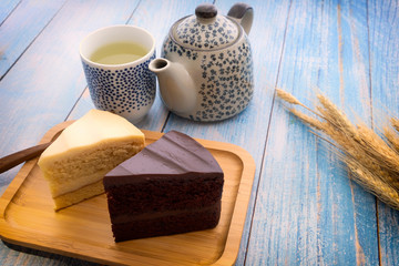 Hot tea with chocolate cake and milk cake on the blue wooden floor