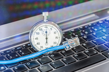 Cable and stopwatch on computer keyboard symbolizing bandwidth of internet connection - obrazy, fototapety, plakaty