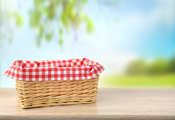Straw empty basket decorated with picnic checkered cloth  nature background.