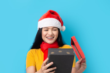 Asian woman in yellow dress wearing red scarf and Santa hat, holidays concept