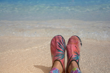 Wading shoes of woman legs on the beach in front of sea