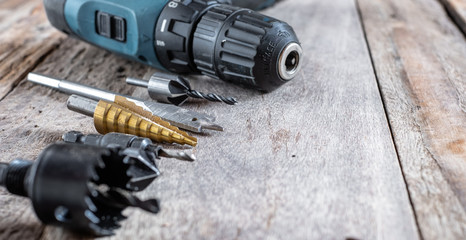 Variety of different types of bit drill with cordless drill displayed on old wooden background. Selective focus.