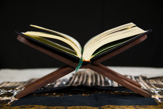 Muslims Islamic Holy Book Quran Majid with Quran wooden stand and Janamaz Prayer Rug and black background