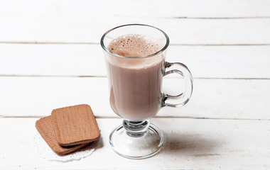 Glass cocoa mug or coffee on white wooden table served cookies