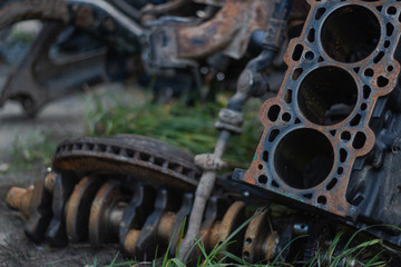 rusty disassembled cylinder block on the ground and in the background lies a rusty crankshaft