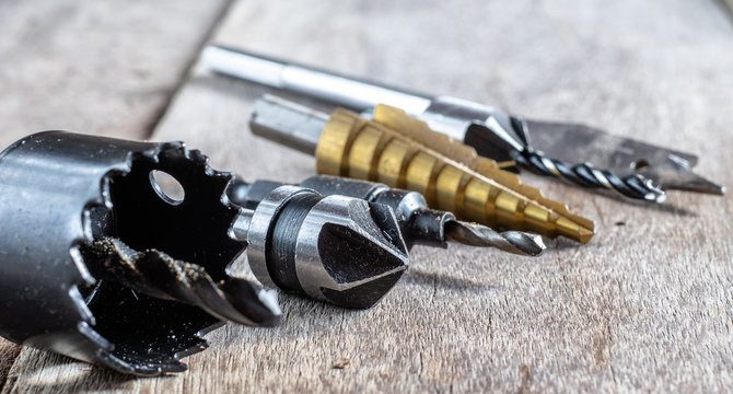 Variety of different types of bit drill displyed on old wooden background. Selective focus.