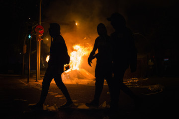 Manifestantes caminan delante de una barricada en llamas.