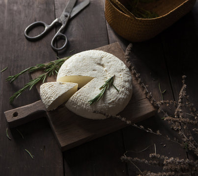 Soft adyghe cheese with fresh rosmarinus on wooden background