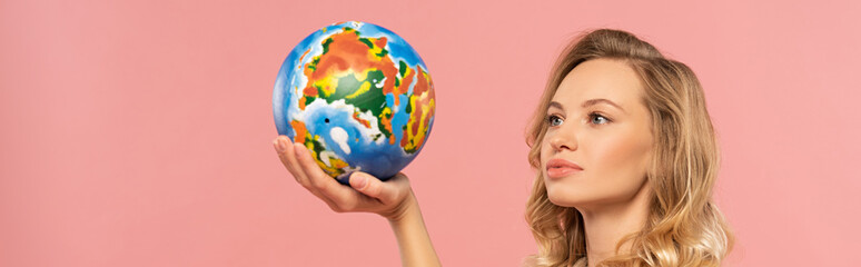Woman holding globe in hand isolated on pink, panoramic shot