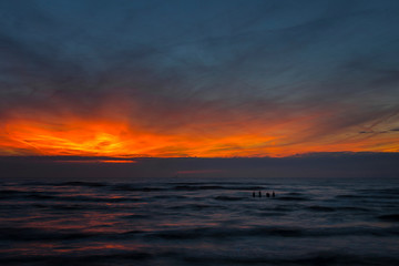 a beautiful sunset looms over the sea in the evening