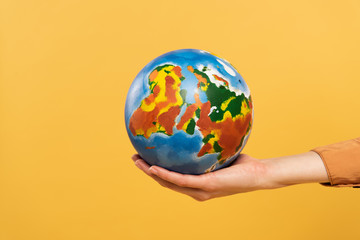 Cropped view of globe in woman hand isolated on yellow
