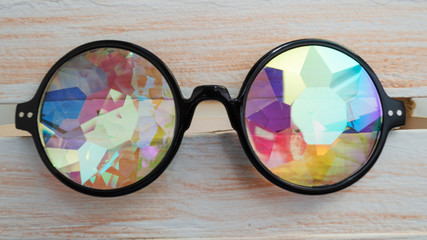 Designer glasses with lenses kaleidoscope on a light wooden background