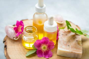 Fototapeta na wymiar Spa skincare setting with oils and natural soap, rosehip oils and flowers, natural spa still life