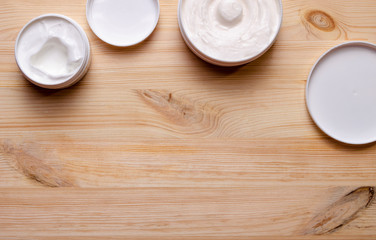 jars of cream for face and body plant wooden background