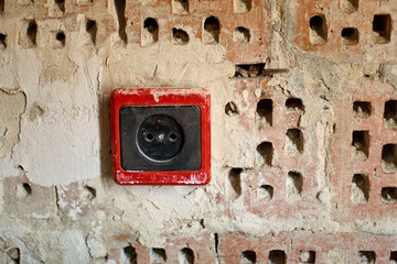 EU power outlet type C, electric point of power at home, on a red brick background with holes