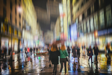 silhouette of people walking on illuminated night city street