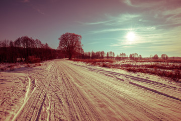 Obraz premium Beautiful pink sunrise over a snowy country road
