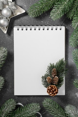 Fototapeta na wymiar Christmas or New year holiday background with open blank Notepad, fir branches and Christmas traditional decorations. Checklist or letter to Santa. Top view with copy space