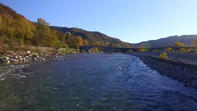 4k forward aerial drone footage flying low on the Trebbia river water and the Gobbo bridge near Bobbio in the Piacenza province, nice small italian town.Nice side  rays light.