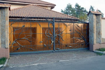 closed wrought iron brown gate and part of the fence 