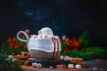 Hot chocolate with marshmallows and a miniature sweet igloo, winter drink concept with copy space. Creative drink photography header