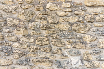 Rough surface of random pattern rastic of brown and light yellow color natural free form sand stone cladding on the concrete wall background