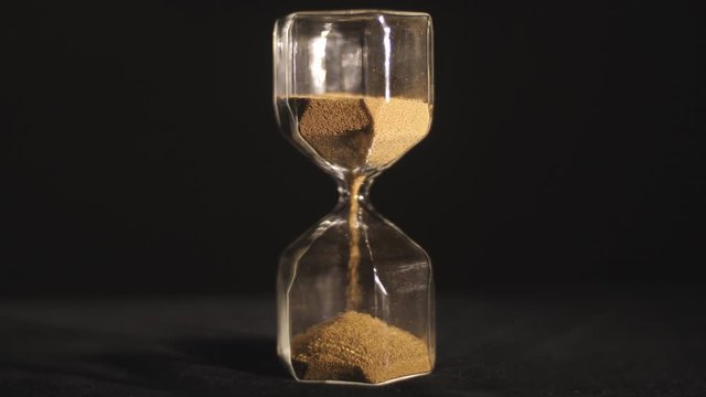 the fall of the sand clock on black background