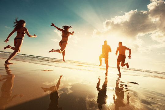 Happy tourists runs at sunset sea beach