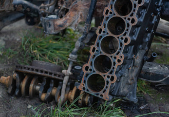 rusty disassembled cylinder block on the ground and in the background lies a rusty crankshaft