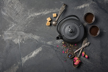 Obraz na płótnie Canvas Black japanese cast iron teapot and flower tea with rose buds