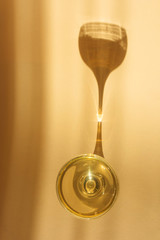 Glass of champagne on a light background. An impressive long shadow falls from the glass. The original concept of the holiday, alcoholic drinks. Minimalism, top view.