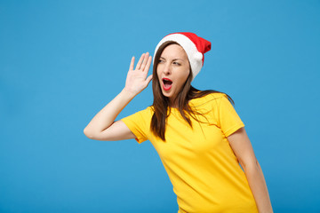 Curious young brunette woman Santa girl in Christmas hat posing isolated on blue background. Happy...