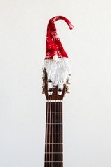 acoustic guitar with red Santa hat. Christmas song music concept on white background