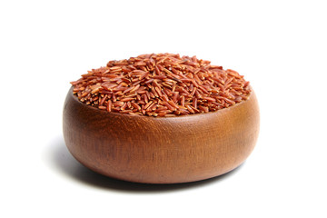 Red rice in a brown wooden bowl isolated on white background. Dry uncooked cereal grains, ingredient for cooking  various dishes