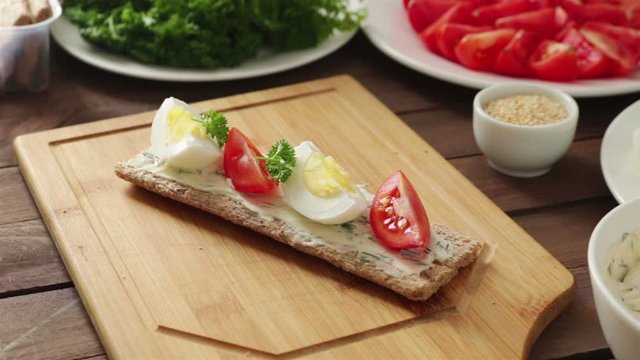 man places parley on healthy sandwich with crispbread boiled egg tomato cream cheese close up