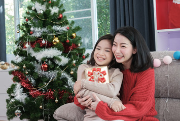 portrait of family with a mother and daughter holding gift box celebrating Christmas night decorated with Christmas trees on Christmas Day.. - 304674464