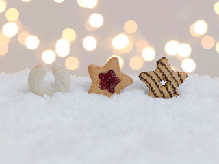 Fototapeta na wymiar colorful christmas cookies on white snow with many small, shining lights in the background