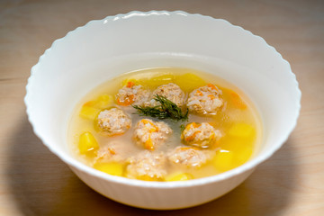 Plate of vegetable soup with meatballs on the wooden table closeup