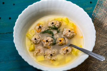 Plate of vegetable soup with meatballs on the wooden table closeup