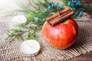 Christmas decoration. Candle and red apple decorated with cinnamon sticks