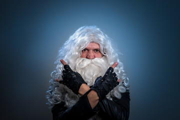 A tough guy in a wig and a beard like Santa Claus makes a heavy metal gesture with his arms folded...