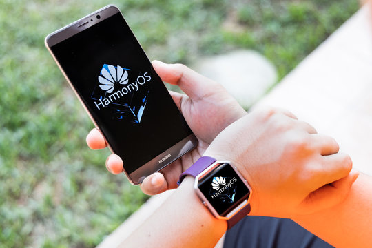KUALA LUMPUR, MALAYSIA, August, 11, 2019: Huawei officially announced its new operating system, HarmonyOS. Illustrative of person wearing smart watch and smart phone with HarmonyOS on screen.