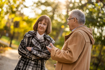 Senior couple is talking in park in autumn.