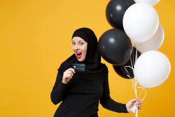 Arabian muslim woman in hijab celebrate hold credit card black white air balloons isolated on...