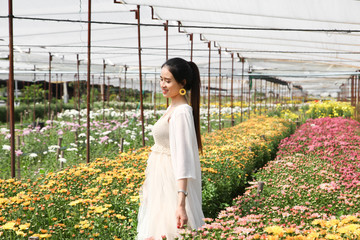 Portrait young beautiful asian woman in white dress relaxing at chrysanthemum flower garden